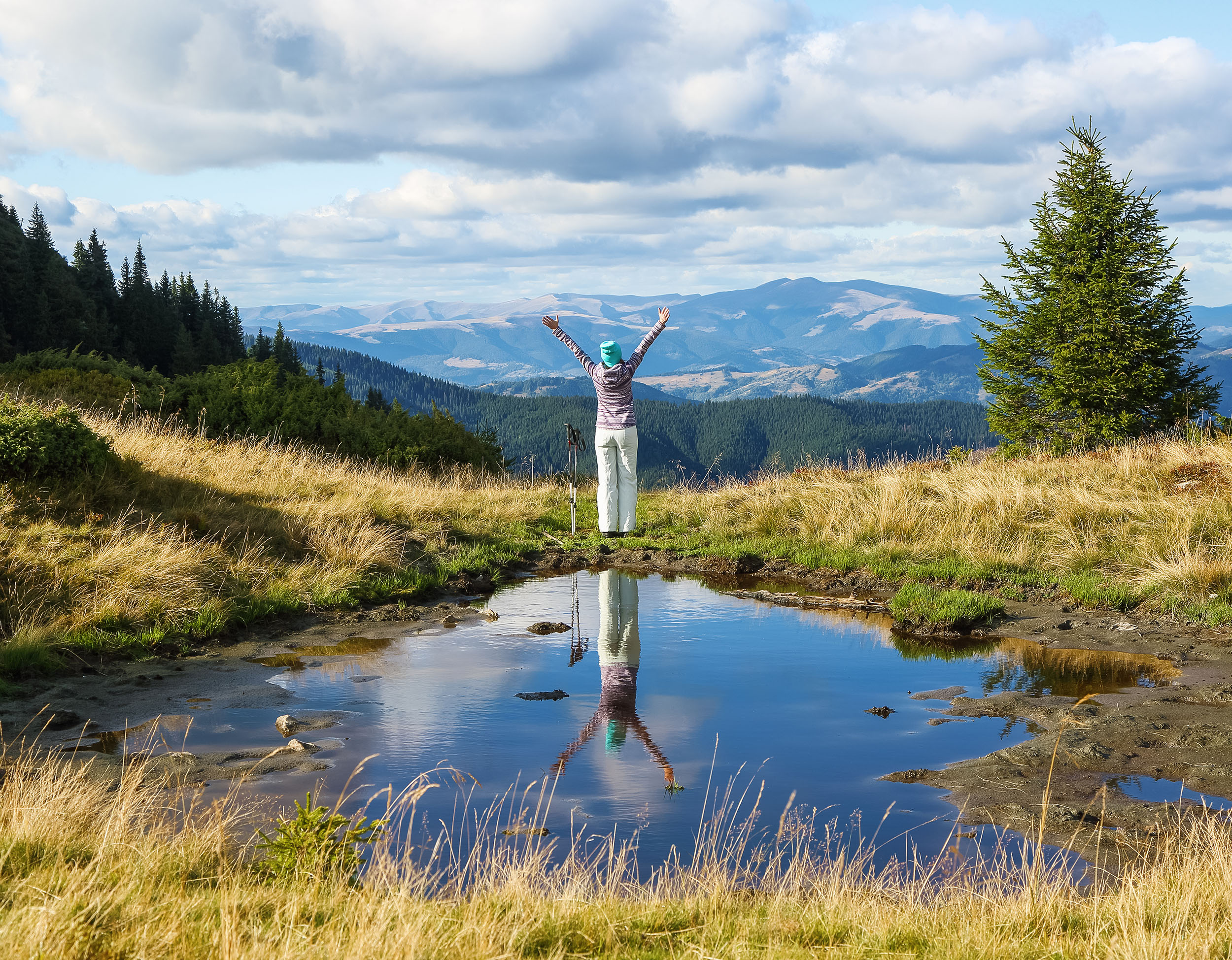 Bergpanorama mit einer Frau, die die Arme ausbreitet – Motiv aus dem Flyer von Zwade Coaching.