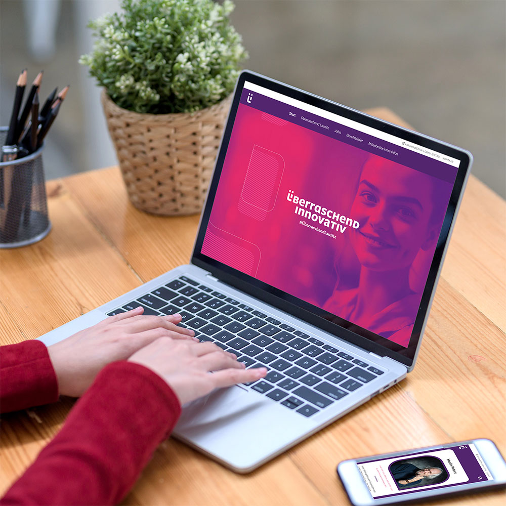Auf Laptop und Handy: pinkfarbene Bühne mit dem Claim „überraschend innovativ“ und dem Porträt einer lachenden Frau.